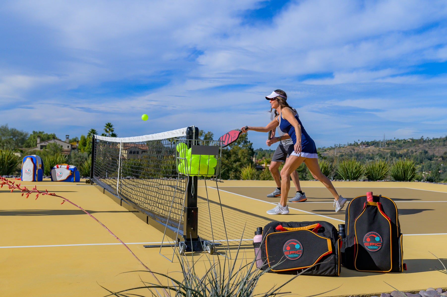 two pickleball players at the net with premium pickleball bags placed
beside the court